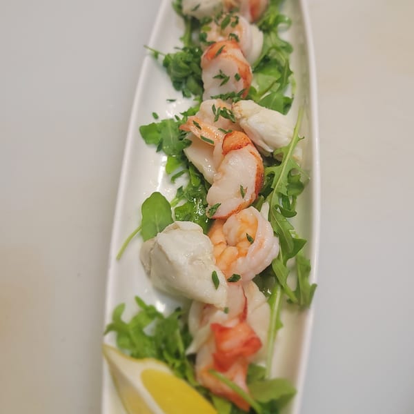 Shrimp and crab meat on a bed of arugula, garnished with parsley and a lemon wedge.