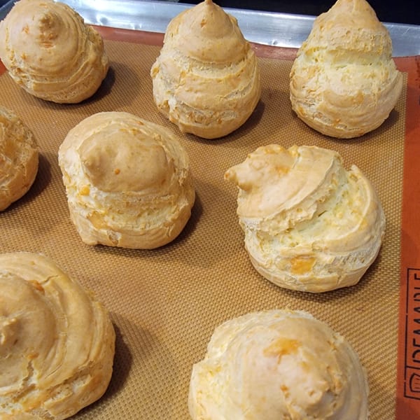 Golden-brown cheese puffs on a baking mat, fresh from the oven.